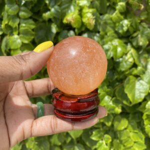 Orange crystal ball on a wooden stand.