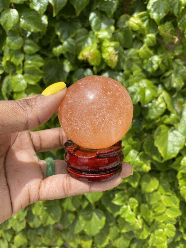 Orange crystal ball on a wooden stand.