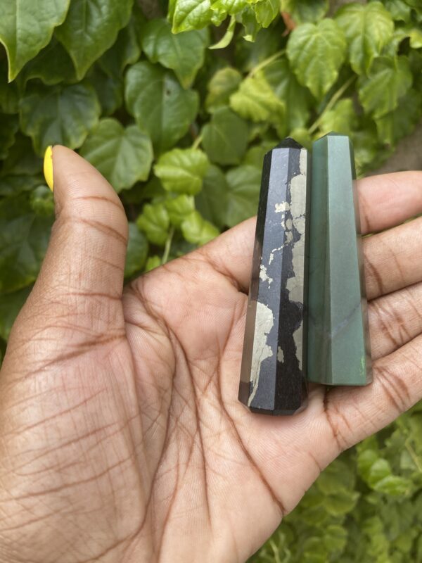 Black and green crystal points in hand.