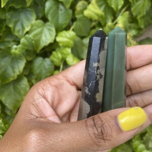 Hand holding two green and black crystal points.