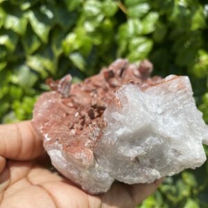 Hand holding a clear and red crystal.