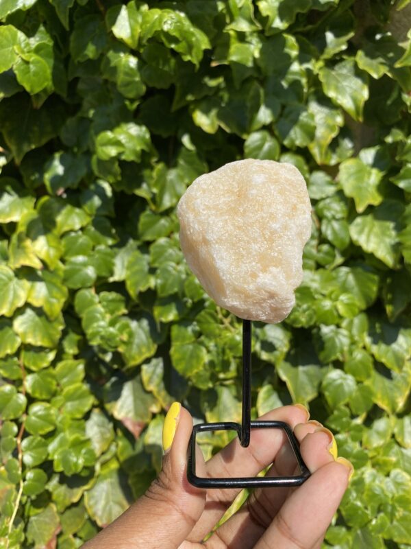 A hand holding a white crystal on a stand.