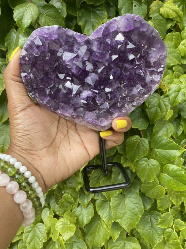 Purple amethyst heart crystal on stand.