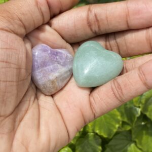 Two heart shaped gemstones in hand.