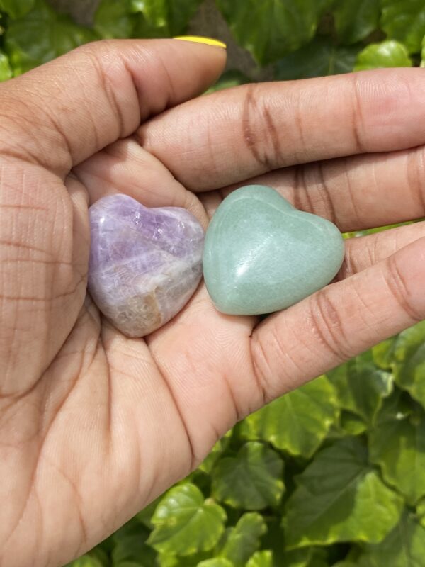 Two heart shaped gemstones in hand.