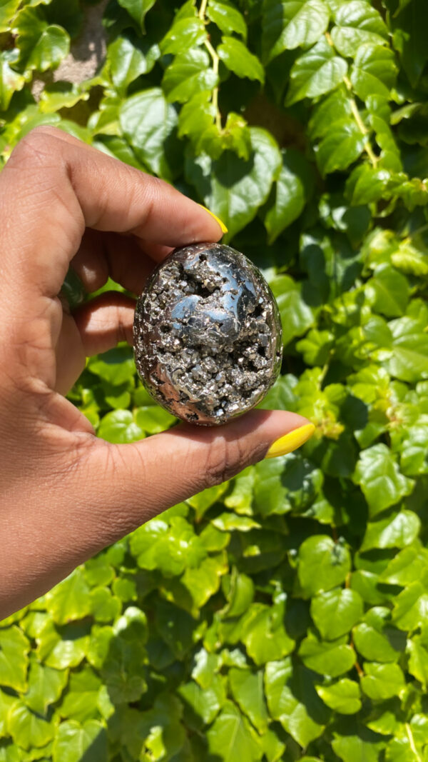 Hand holding a pyrite crystal egg.