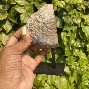 Hand holding a grey agate on a stand.