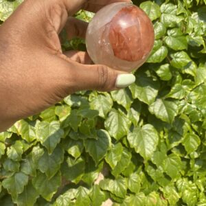 Hand holding a red and clear crystal ball.