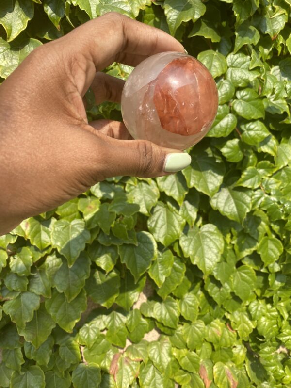 Hand holding a red and clear crystal ball.