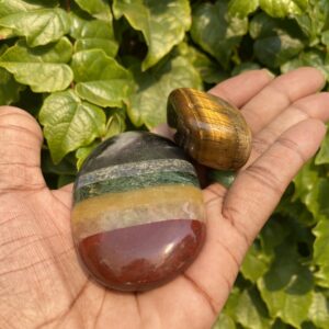 Hand holding two colorful gemstones.