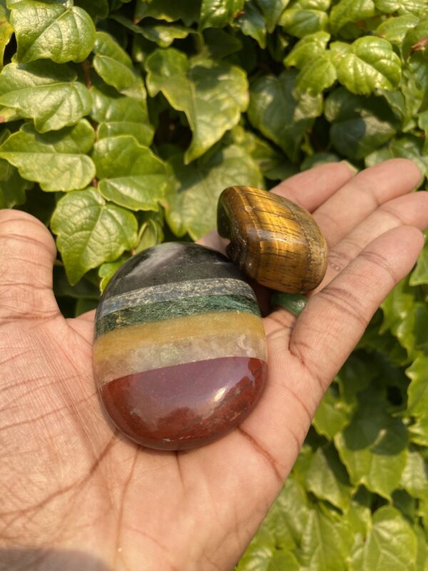 Hand holding two colorful gemstones.