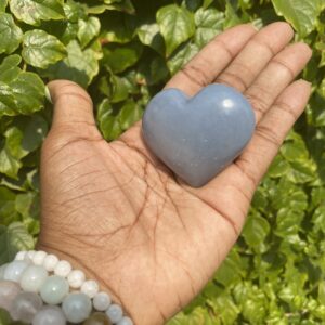 Hand holding a blue heart-shaped stone.