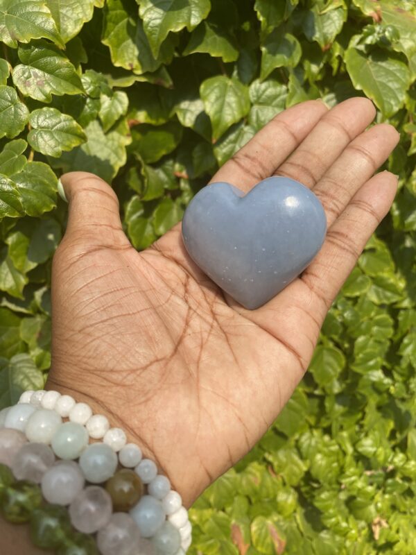 Hand holding a blue heart-shaped stone.