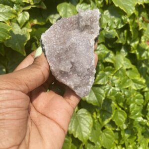 Hand holding a purple amethyst crystal.