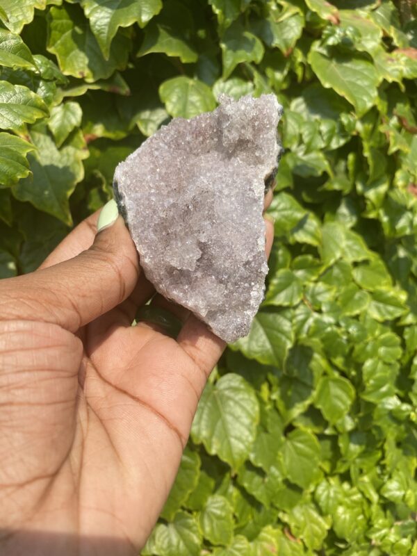 Hand holding a purple amethyst crystal.