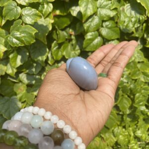 Hand holding a light blue gemstone.