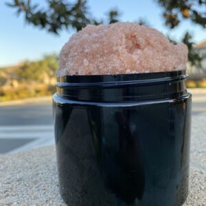 Pink salt scrub in a black jar.