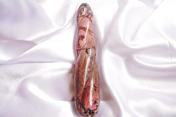 Pink and brown gemstone on white fabric.