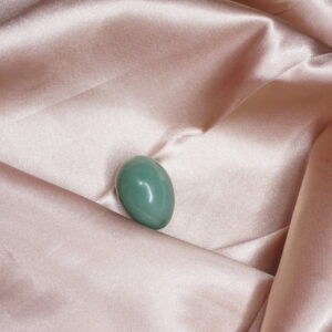 Green gemstone on pink satin fabric.