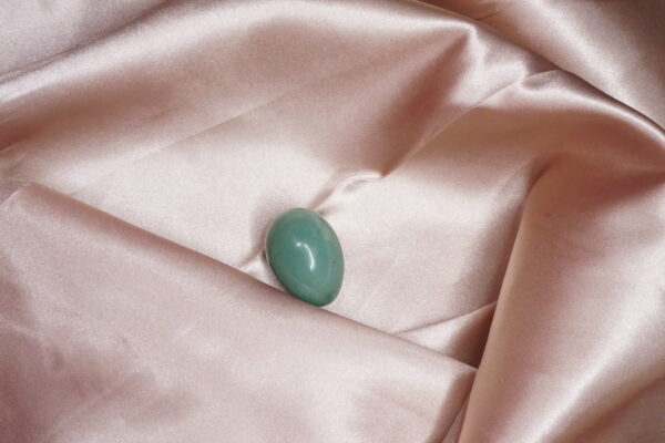 Green gemstone on pink satin fabric.