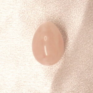 Pink oval gemstone on white fabric.