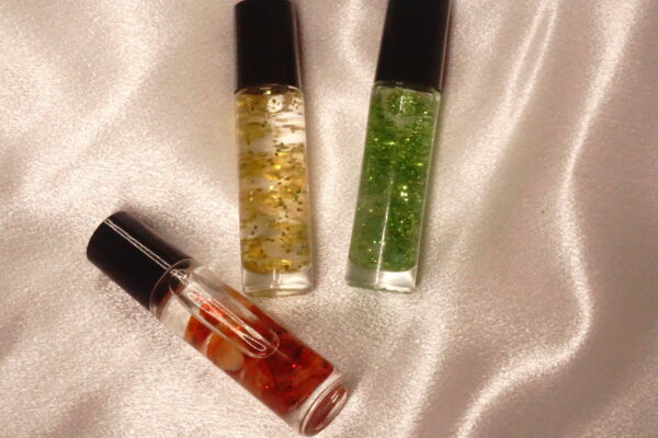 Three glitter roll-on bottles on fabric.