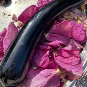 Black obsidian yoni egg on rose petals.