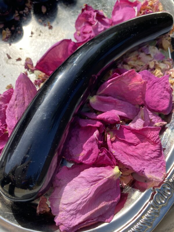 Black obsidian yoni egg on rose petals.