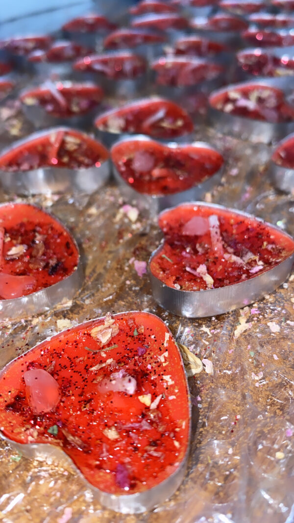 Red heart-shaped candles with glitter and petals.