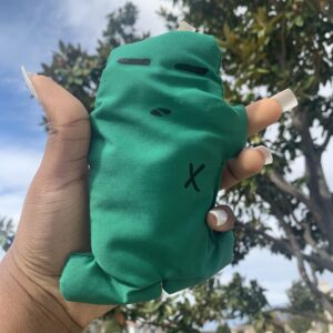 Green hand-sewn plush toy with an X.