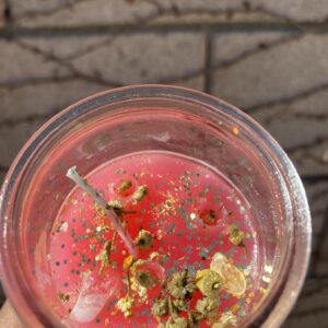 Pink candle with glitter and dried flowers.