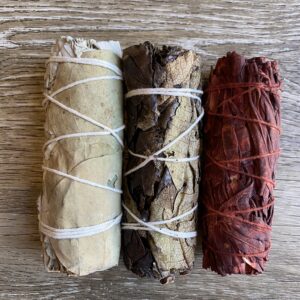 Three smudge sticks on a wooden background.