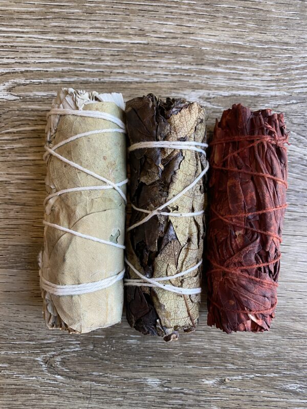 Three smudge sticks on a wooden background.