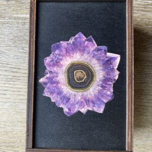 Amethyst crystal in a wooden frame.