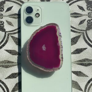 A phone with a slice of pink agate on top