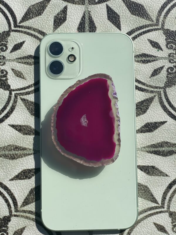 A phone with a slice of pink agate on top