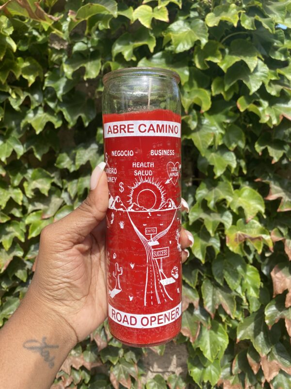 A person holding onto a candle with the words " abre camino " written on it.