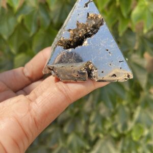 A hand holding a piece of metal with some dirt on it