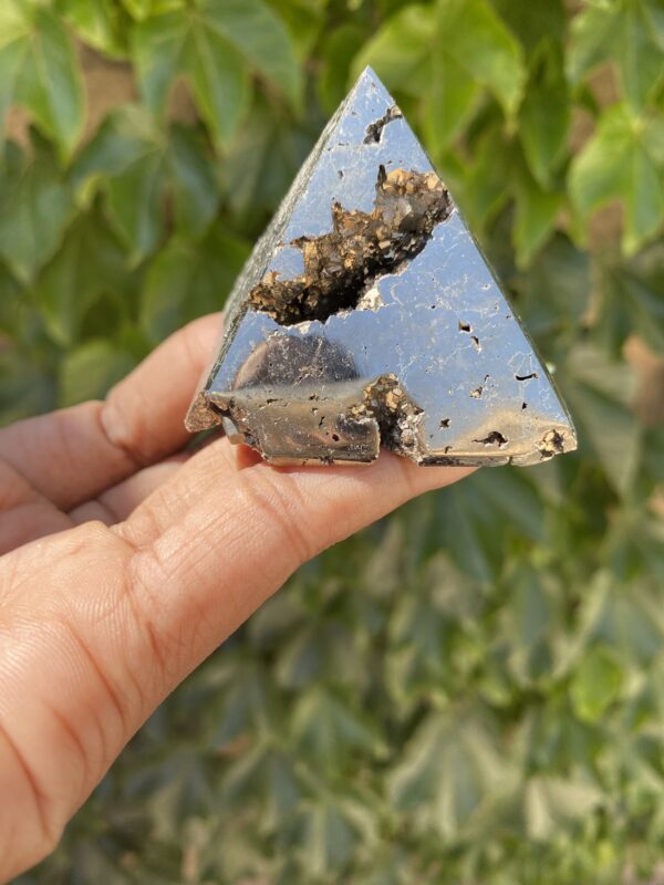 A hand holding a piece of metal with some dirt on it