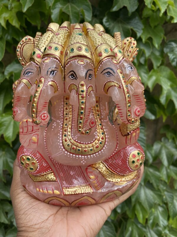 A hand holding an elephant statue in front of some bushes.