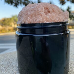 A black container with pink rock on top of it.