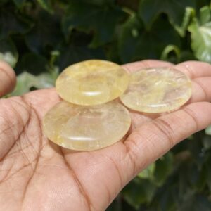 A person holding three yellow stones in their hand.