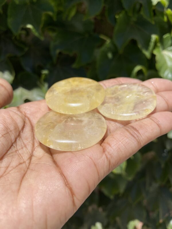 A person holding three yellow stones in their hand.