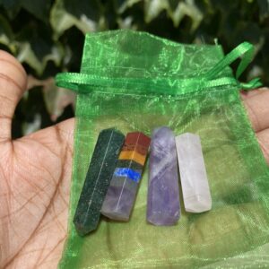 A person holding up a bag of four different colored stones.