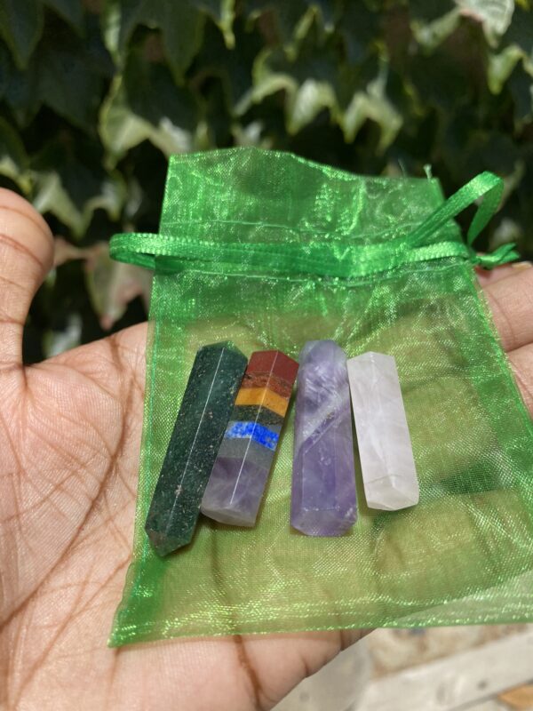 A person holding up a bag of four different colored stones.