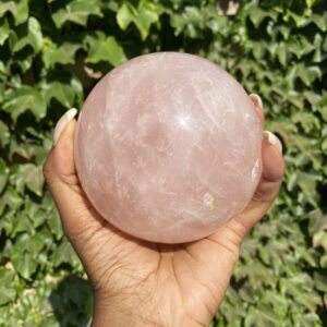 A person holding a large pink crystal ball.