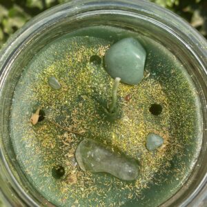 A jar of green stuff is sitting on the ground.