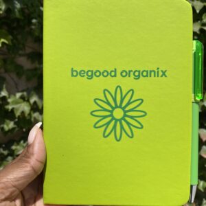 A person holding up a notebook with the words " begood organix ".