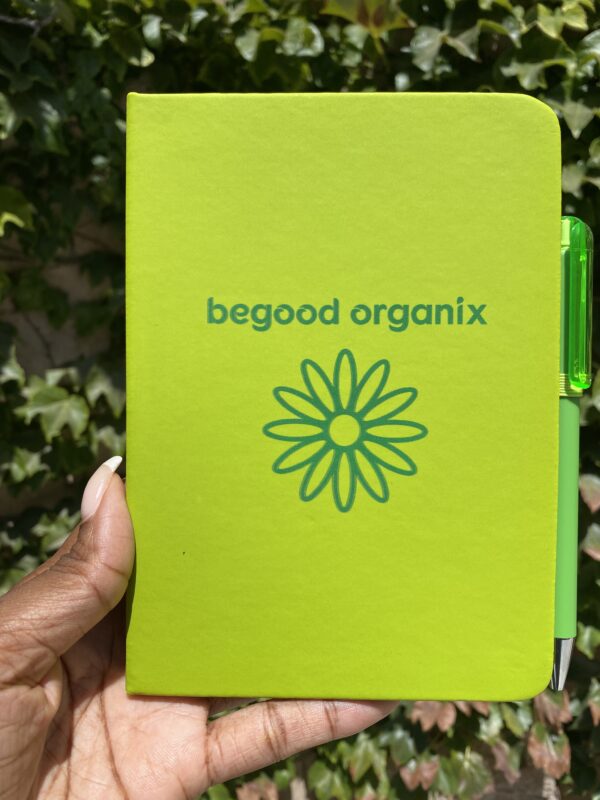 A person holding up a notebook with the words " begood organix ".