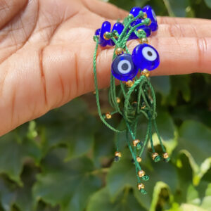 A person holding something with evil eye beads on it.